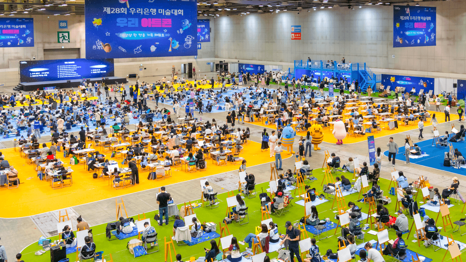 대형 행사장에서 수많은 학생들이 다같이 그림을 그리고 있는 모습